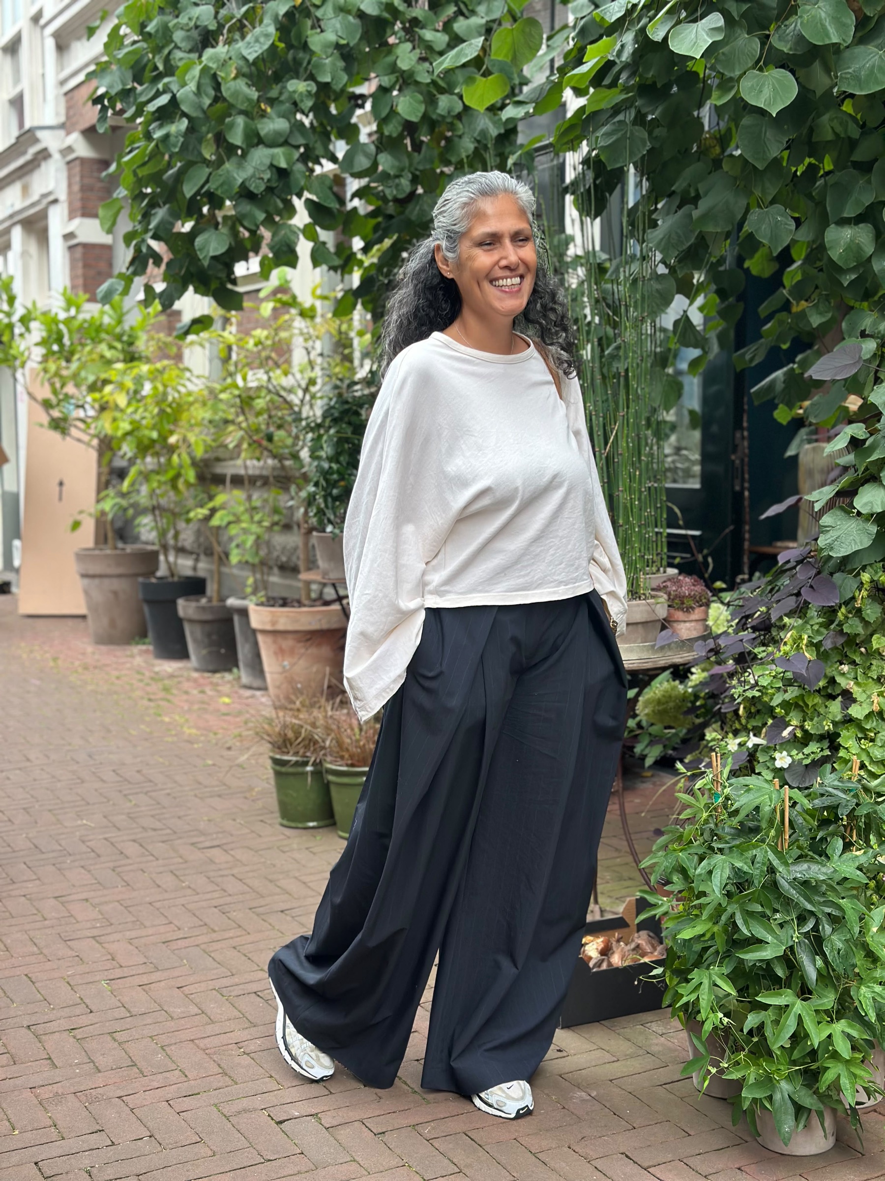Danielle loopt glimlachend door een groene straat en kijkt ontspannen voor zich uit.